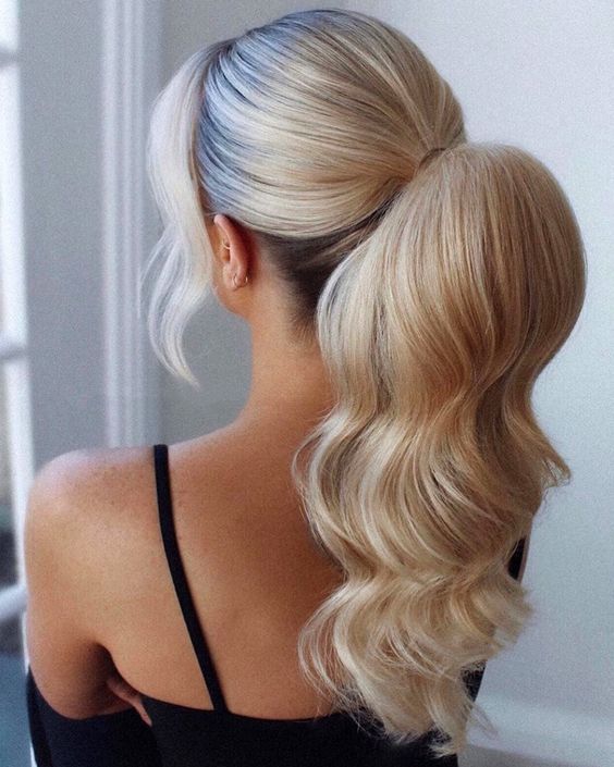 bridal hairstyle idea on blonde hair with ponytail and soft waves, with loose hair strands around the face.