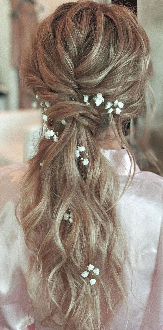 boho style bridal hair with messy low ponytail, relaxed waves and delicate baby’s breath flowers around it