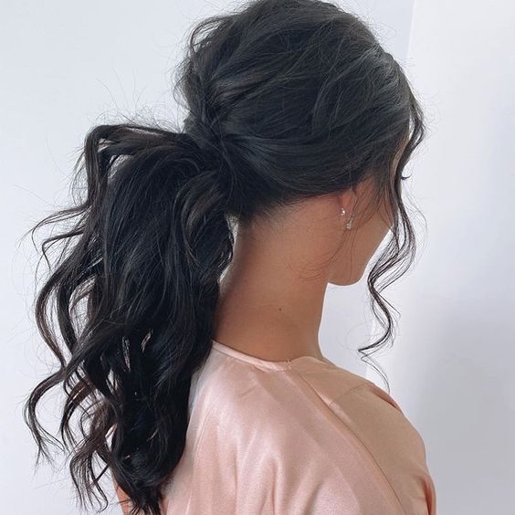 bridal hairstyle idea on brunette hair. messy waves on a low ponytail and loose strands around the face
