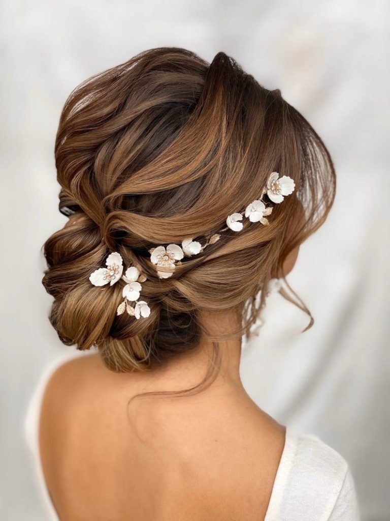 blonde bride wearing her hair in a low bun with delicate floral hair accessory