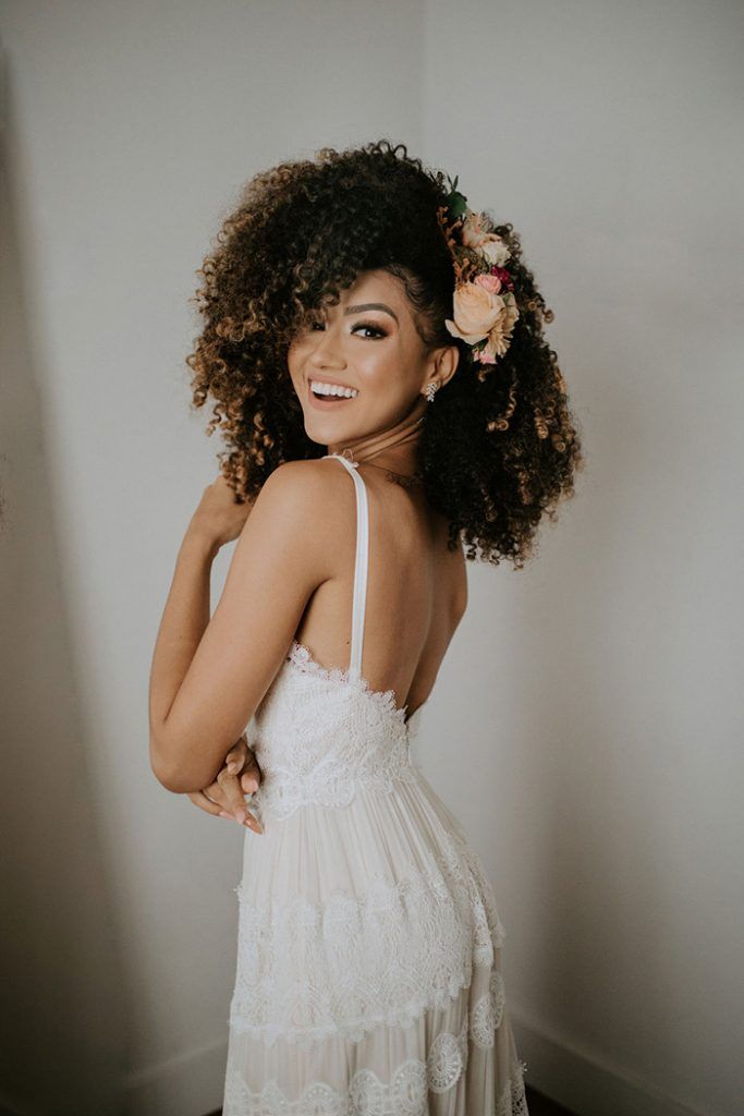 bride smiling with big natural curly hair embellished with flowers