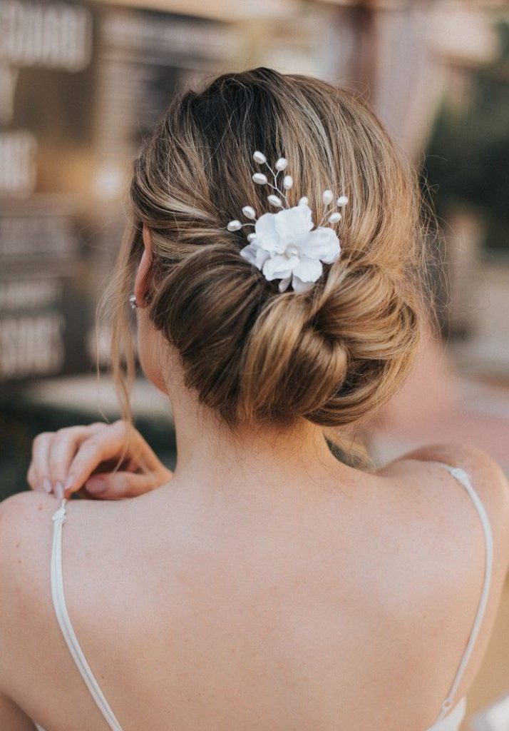 blonde bride wearing her hair in a low bun with small floral hair accessory