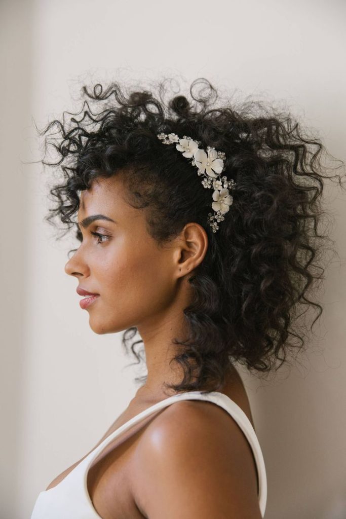 natural curly hair bride with hair parted to the side and floral hairpiece for wedding