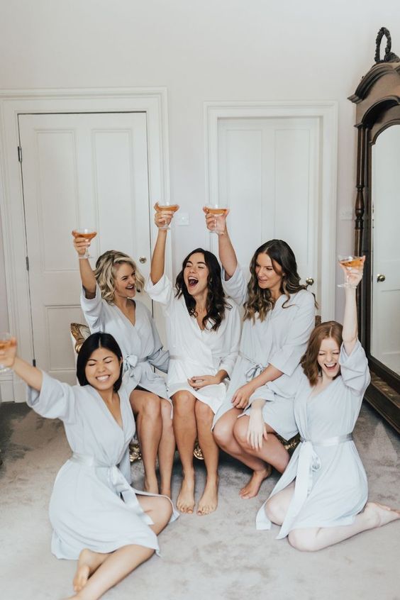 bridal party and bride getting ready photo wearing robes and holding a glass up 