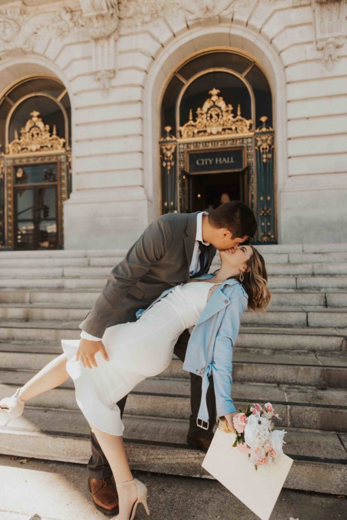 bride and groom sharing a kiss in front of the city hall after their civil wedding