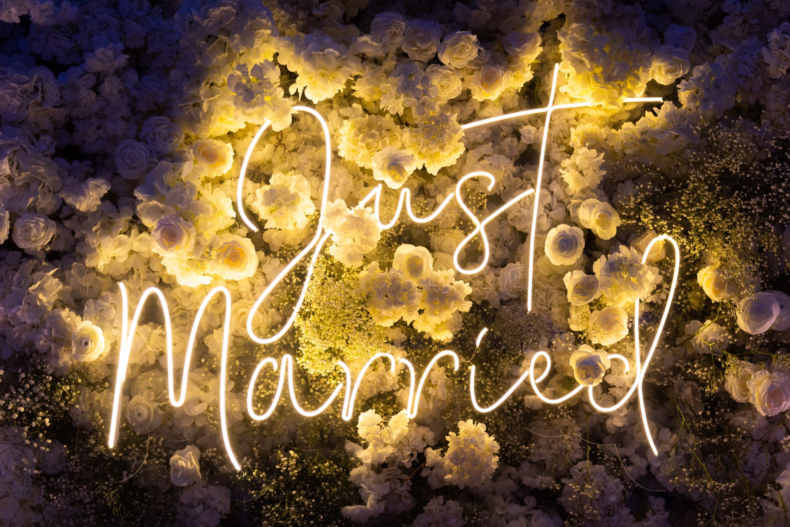 wedding wall backdrop with white flowers and led signs saying just married